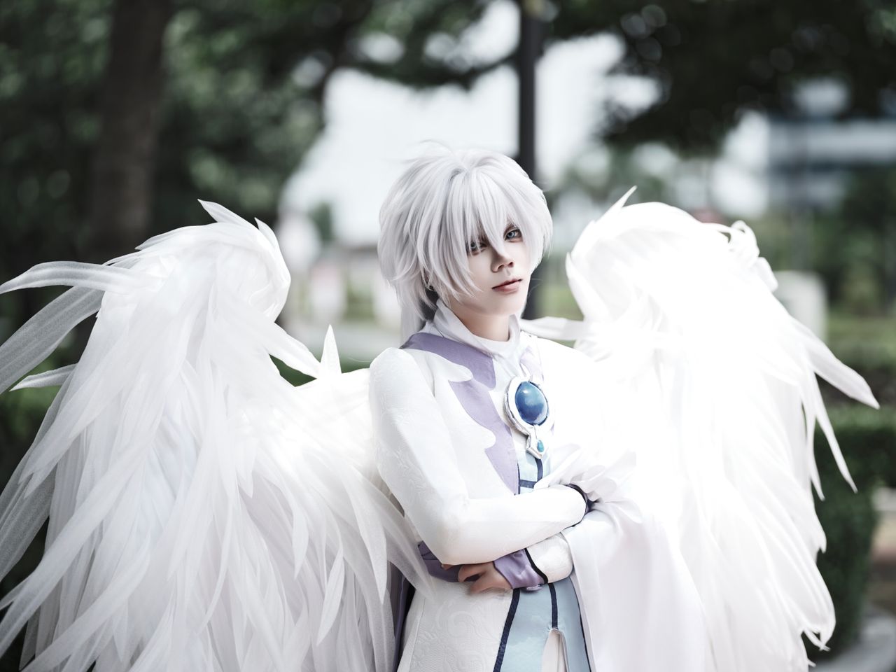Graceful angelic cosplay with white wings and divine attire captured outdoors.